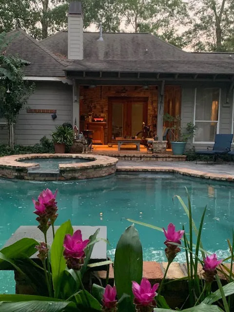 Backyard pool with lush landscaping beside a custom home